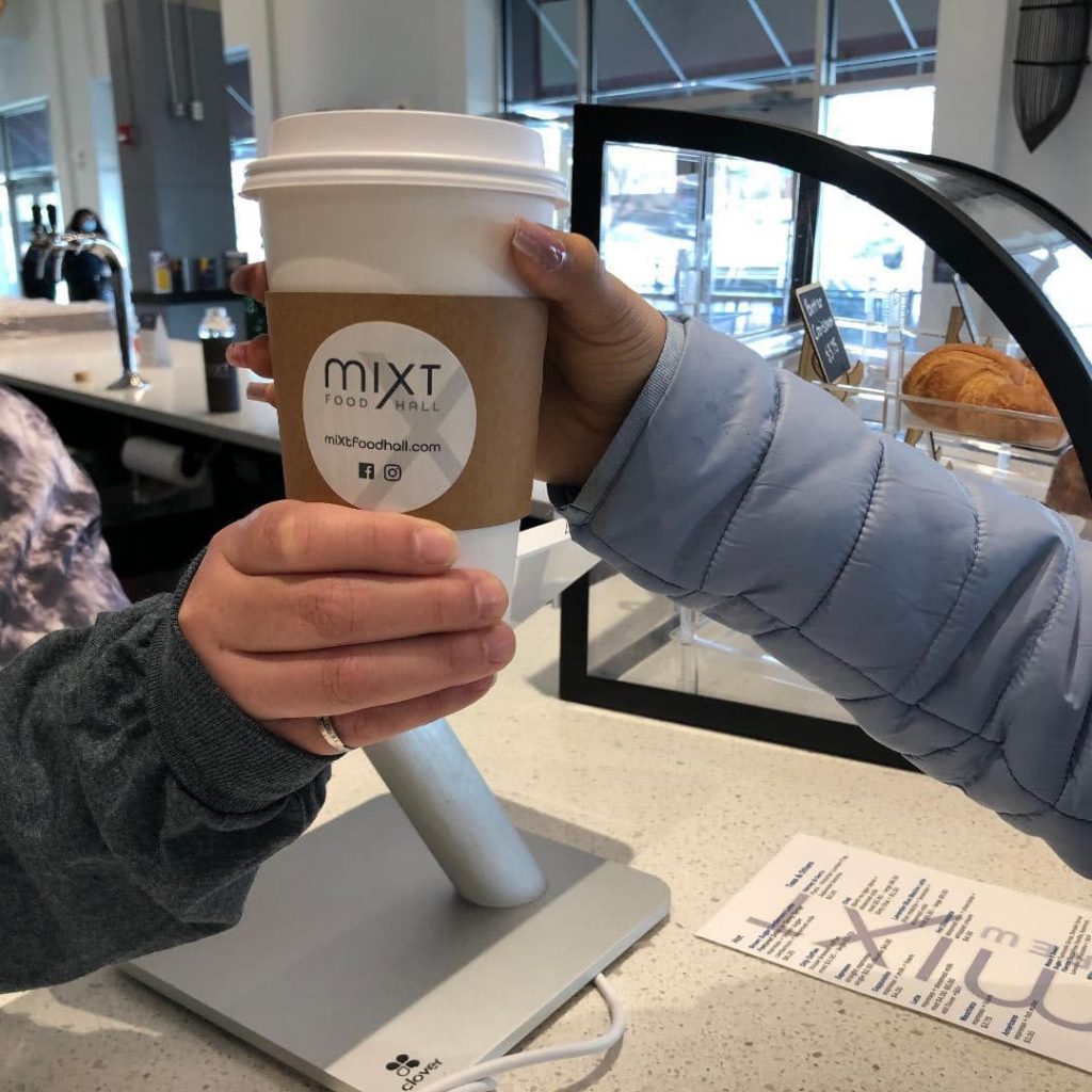 A worker handing a customer a cup of coffee